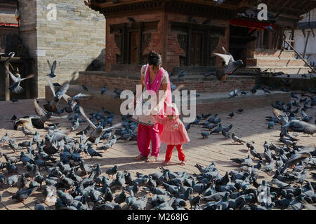 Mutter und Kleinkind Mädchen zu Fuß am Durbar Square, Kathmandu, Nepal von fliegenden Straße Tauben umgeben Stockfoto