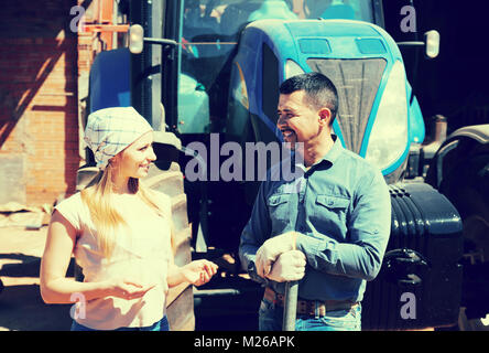 Positive männliche und weibliche Landwirte neben großen Feld Motor und Reden Stockfoto