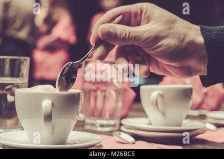 Männliche hand Kaffeelöffel heißen Cappuccino im Café oder Restaurant zu rühren Stockfoto