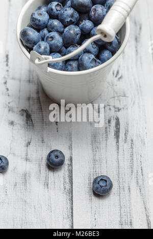 Heidelbeeren in weißen Blecheimer auf weißem Holz Hintergrund Stockfoto