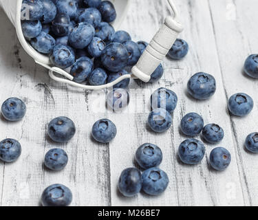 Heidelbeeren in weißen Blecheimer auf weißem Holz Hintergrund Stockfoto