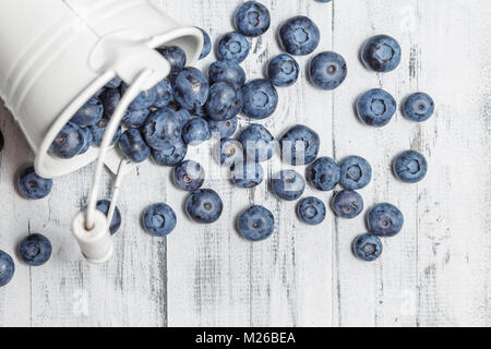 Heidelbeeren in weißen Blecheimer auf weißem Holz Hintergrund Stockfoto