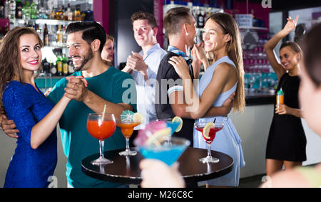 Freudige Frauen mit Männern tanzen Paarweise оn der Tanzfläche in der Diskothek Stockfoto