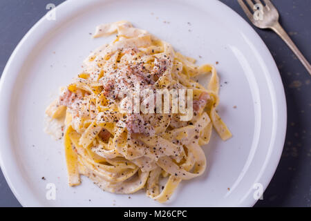 Nahaufnahme der Pasta Carbonara, auf eine weiße Platte mit einem dunklen Hintergrund Stockfoto
