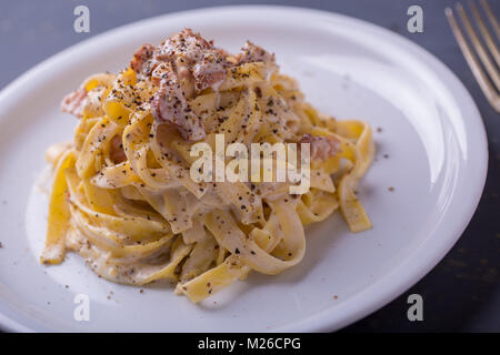 Nahaufnahme der Pasta Carbonara, auf eine weiße Platte mit einem dunklen Hintergrund Stockfoto