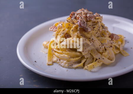 Nahaufnahme der Pasta Carbonara, auf eine weiße Platte mit einem dunklen Hintergrund Stockfoto