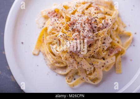 Nahaufnahme der Pasta Carbonara, auf eine weiße Platte mit einem dunklen Hintergrund Stockfoto