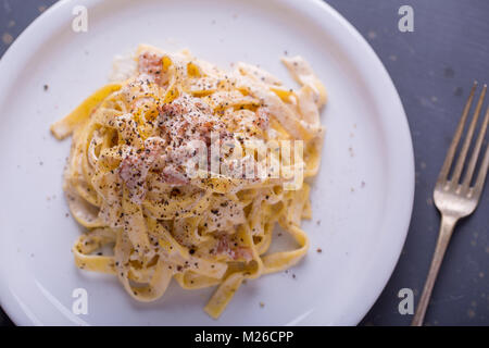 Nahaufnahme der Pasta Carbonara, auf eine weiße Platte mit einem dunklen Hintergrund Stockfoto