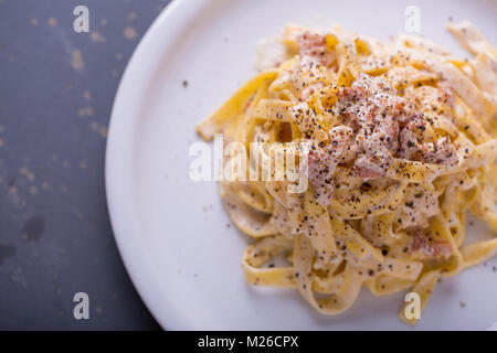 Nahaufnahme der Pasta Carbonara, auf eine weiße Platte mit einem dunklen Hintergrund Stockfoto