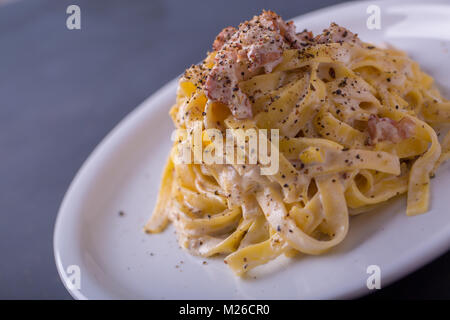 Nahaufnahme der Pasta Carbonara, auf eine weiße Platte mit einem dunklen Hintergrund Stockfoto