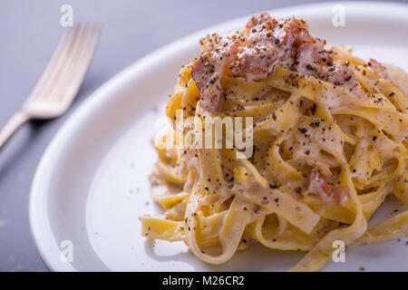 Nahaufnahme der Pasta Carbonara, auf eine weiße Platte mit einem dunklen Hintergrund Stockfoto