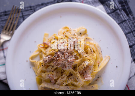 Nahaufnahme der Pasta Carbonara, auf eine weiße Platte mit einem dunklen Hintergrund Stockfoto