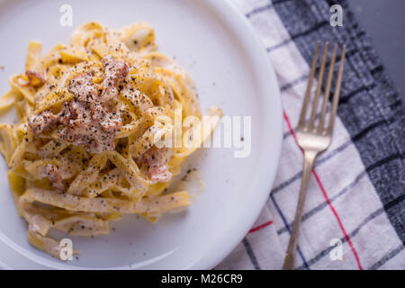 Nahaufnahme der Pasta Carbonara, auf eine weiße Platte mit einem dunklen Hintergrund Stockfoto
