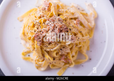 Nahaufnahme der Pasta Carbonara, auf eine weiße Platte mit einem dunklen Hintergrund Stockfoto