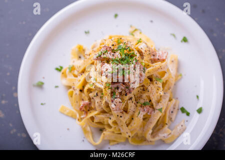 Nahaufnahme der Pasta Carbonara, auf eine weiße Platte mit einem dunklen Hintergrund Stockfoto