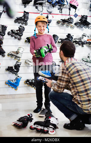 Männliche Shop Assistant hilft jungen auf Walze zu versuchen - Skates, Sportgeschäft Stockfoto