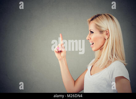 Seitenansicht des jungen Inhalt blonde Holding Zeigefinger bis in neue Idee. Stockfoto