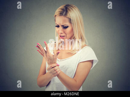 Frau mit Schmerzen in der Hand berühren, Handgelenk und runzelte die Stirn. Stockfoto