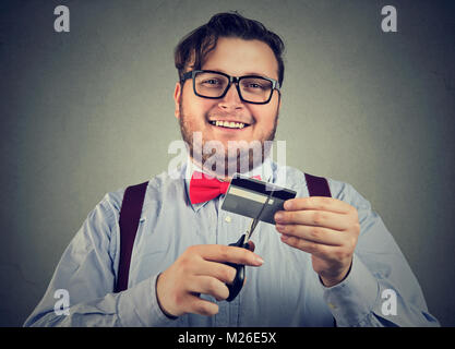 Fröhliche chunky Mann Schneiden per Kreditkarte zahlt, alle Schulden. Stockfoto