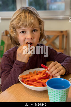 Junge, 7 Jahre alt, isst Gemüse, Paprika und Karotten Stücke, Stockfoto