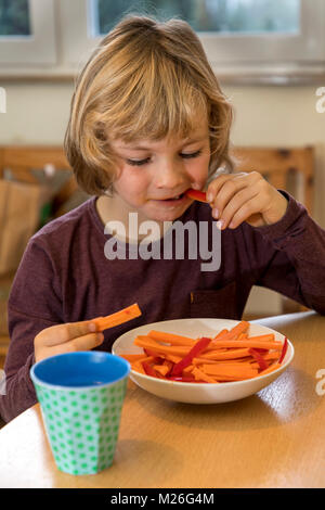 Junge, 7 Jahre alt, isst Gemüse, Paprika und Karotten Stücke, Stockfoto