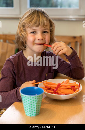 Junge, 7 Jahre alt, isst Gemüse, Paprika und Karotten Stücke, Stockfoto