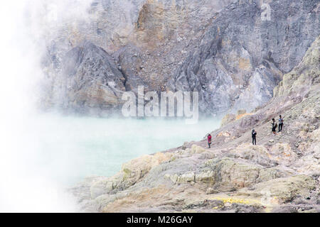 Touristen, die größte stark sauer Kratersee der Welt im Inneren Kawah Ijen, einem Verbund Vulkan in Ostjava, Indonesien. Stockfoto