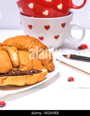 Gebackene Croissants mit Schokolade auf eine weiße Platte, die hinter dem Lagerring Stockfoto