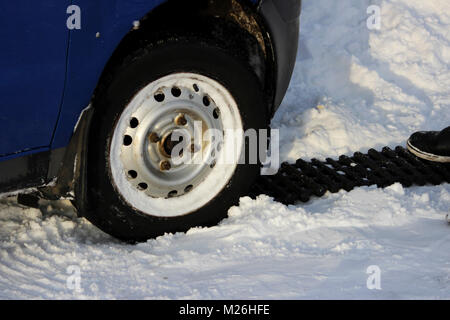 Schwarz Anti-Rutsch-Matte von einer rechteckigen Form befindet sich unter dem Lenkrad eines low-nivellierten Auto, nachdem es in einer schneeverwehung festsitzt, und rutscht. Stockfoto