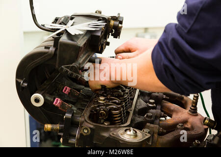 Ein junger Mann Lehrling arbeitet auf einem Auto Motor während der Ausbildung Mechaniker. Stockfoto