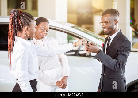 Absatzlage im Autohaus, junge afrikanische Paar erhält der Schlüssel für neue Pkw Stockfoto