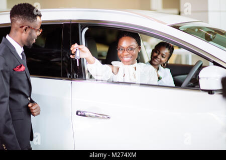 Absatzlage im Autohaus, junge afrikanische Paar erhält der Schlüssel für neue Pkw Stockfoto