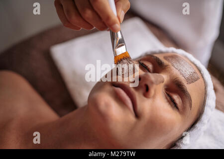 Schöne Frau mit Gesichtsmaske im Beauty Salon. In der Nähe von Spa Therapie für junge Frau in kosmetische Maske. Stockfoto