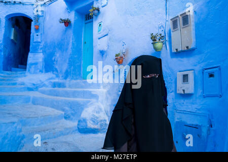 Arabische Frau mit Gesicht mit schwarzen Niqab in Chefchaouen, die blaue Stadt bedeckt, in Marokko Stockfoto