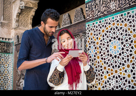 Arabische Paar auf Handy und lächelnd Stockfoto