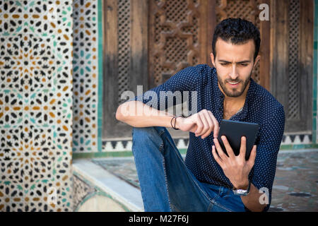 Junge muslimische Menschen in Freizeitkleidung auf Tablet im traditionellen arabischen Ambient Stockfoto