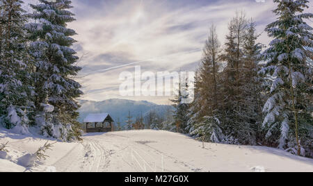 Gartenlaube aus Holz in der Nähe von Mountain Trail. Winter sonniger Tag und dunstige Berge im Hintergrund. Kremnica Berge, Slowakei, Europa. Stockfoto