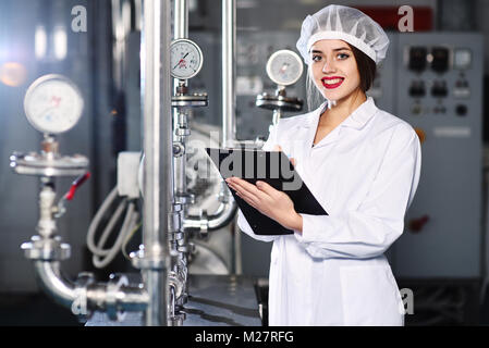 Mädchen ist ein Hinweis auf Papier vor dem Hintergrund der Betriebseinrichtungen Stockfoto