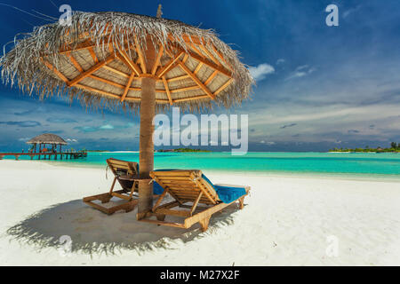 Zwei Stühlen und Sonnenschirm am tropischen Strand in Malediven Stockfoto