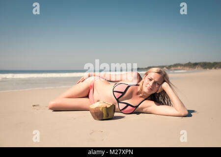 Junge kaukasier Frau genießen ein Urlaubstag mit einer frischen Kokosnuss an einem Strand in Mexiko Stockfoto