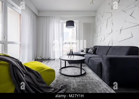 Grüner sack Stuhl, schwarzes Sofa und dekorative 3D-Wand in der Wohnung Stockfoto