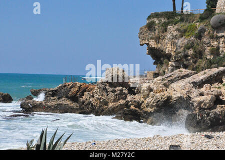 Cliffside mit Boot im Hintergrund und Wellen Stockfoto