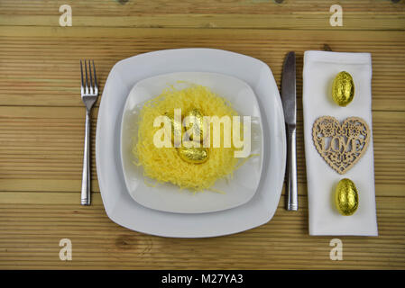 Ostern Tisch Einstellung mit Verzierungen aus einem Nest und Schokolade Ostereier Stockfoto