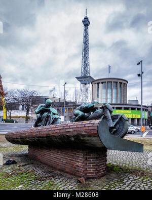 Berlin-Westend, Bronze Skulptur von zwei Motorrad fahrer. Denkmal für Motorradfahrer mit der Berliner Funkturm und Messegelände Gebäude Stockfoto