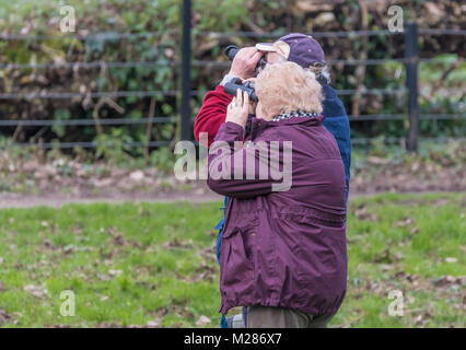 Ältere Paare durch ein Fernglas birdwatching im Winter in England, Großbritannien. Stockfoto
