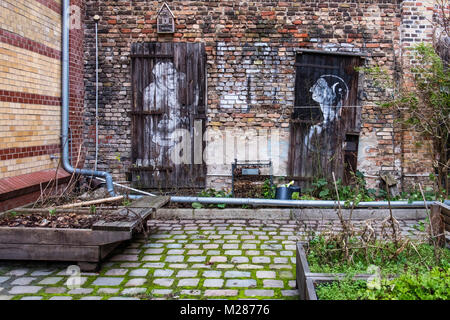 Berlin, Prenzlauerberg Innere gepflasterten Innenhof der ehemaligen Königstadt Brauerei. Gemeinschaftlicher Garten mit Hochbeeten und alte Kunstwerke auf verwitterte Wand Stockfoto