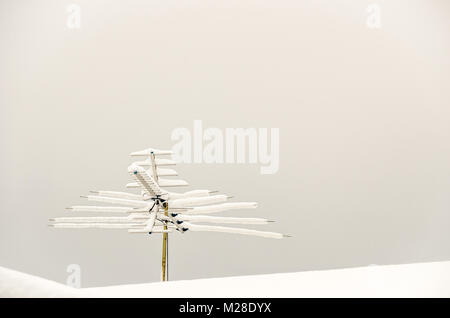 Fernsehen Antenne mit Schnee auf einem Schnee-bedeckten Dach Stockfoto