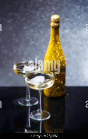 Verschwommenes Foto der Flasche Wein und zwei Weingläser auf schwarz Tabelle Stockfoto