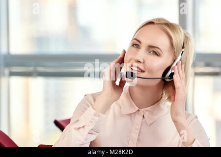 Portrait der Unternehmerin im Gespräch über das Headset telefonieren. Weibliche customer support Operator mit Headset und lächelnd in helles Zimmer. Holding Headset benötigten Stockfoto