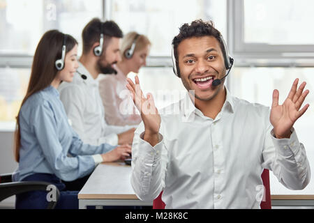 Portrait von extrem glücklich schwarz Call Center Betreiber. Heiter froh schwarz Fahrer gegen die arbeitende Bevölkerung im Amt. Stockfoto
